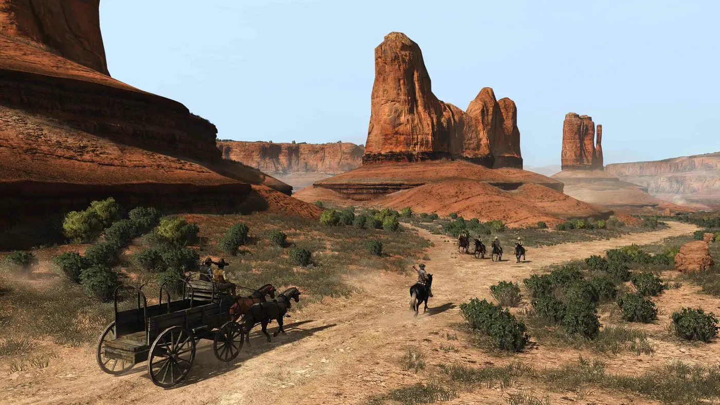 A stagecoach and riders crossing a vast valley of red rocks and desert buttes under a clear sky in Red Dead Redemption