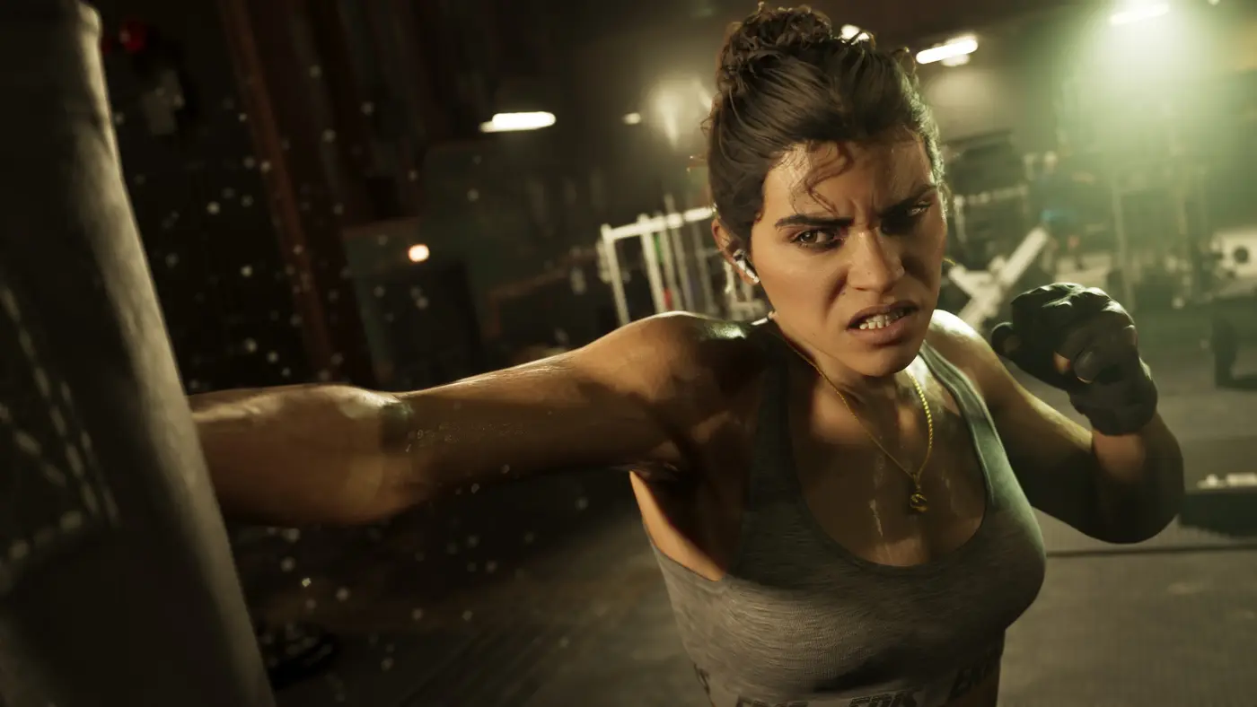 Lucia Caminos alone in a gym, hitting a punching bag, gray tank top and gloves, focused and tense expression