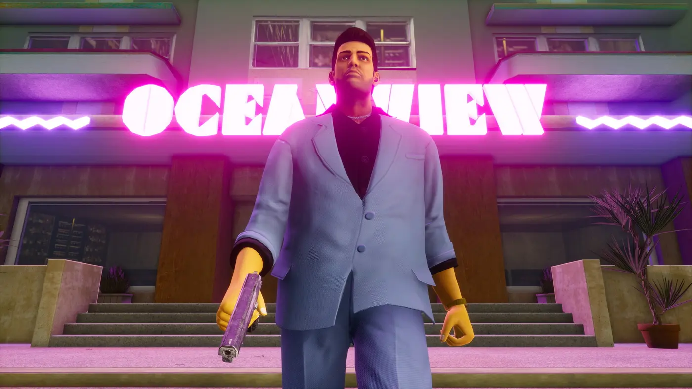 Character in a pastel suit holding a pistol in front of the Ocean View hotel and its pink neon sign, at night, in GTA Vice City
